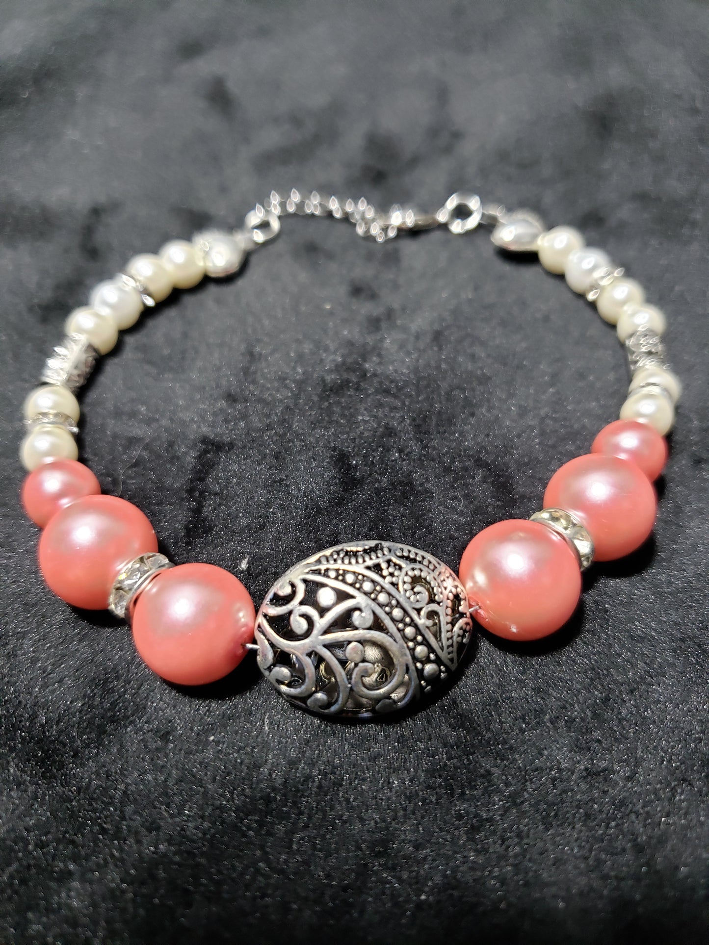 Beaded bracelet with pink and white beads and an ornate silver clasp on a dark background
