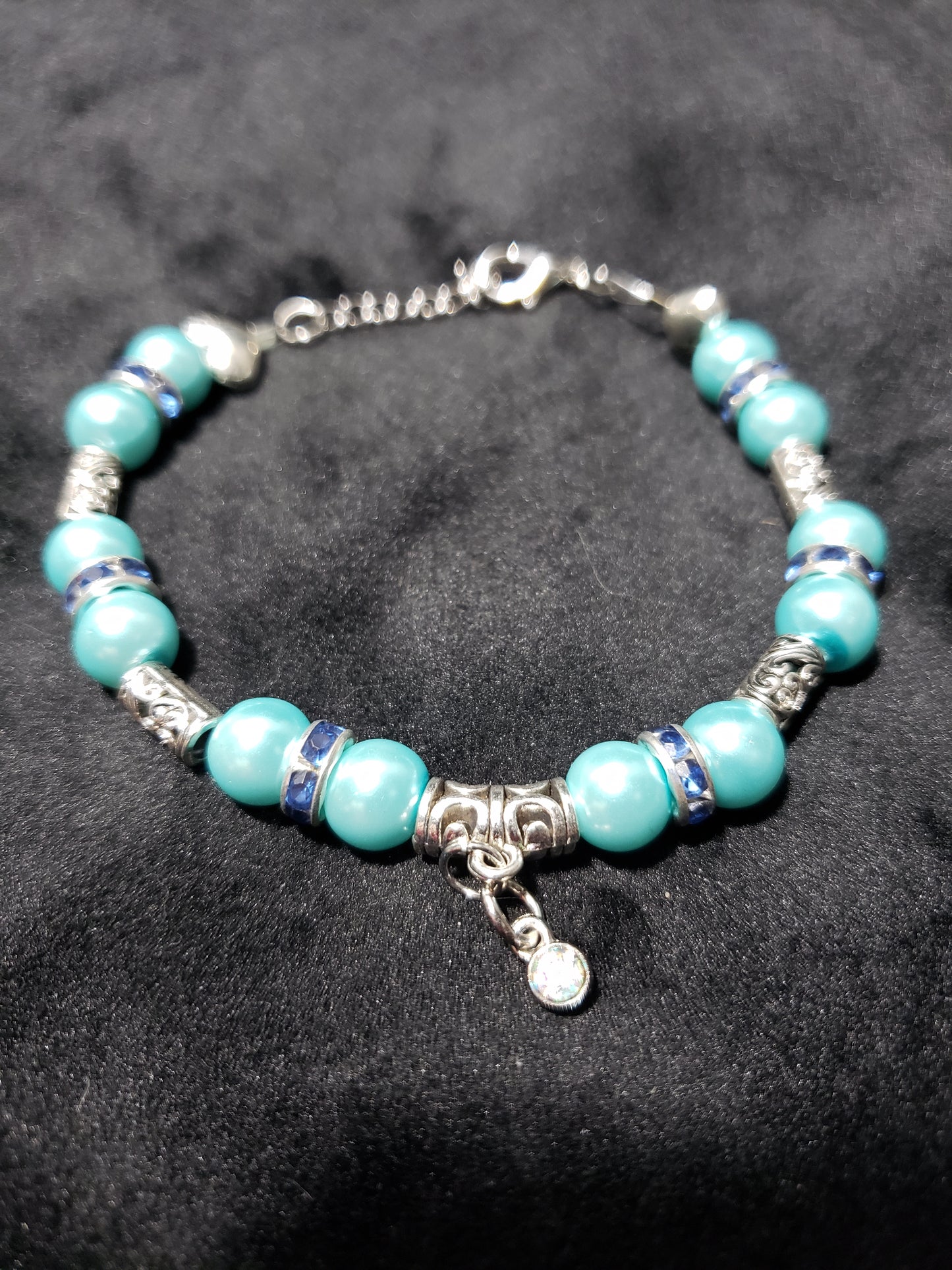 Blue beaded bracelet with silver accents on a black background