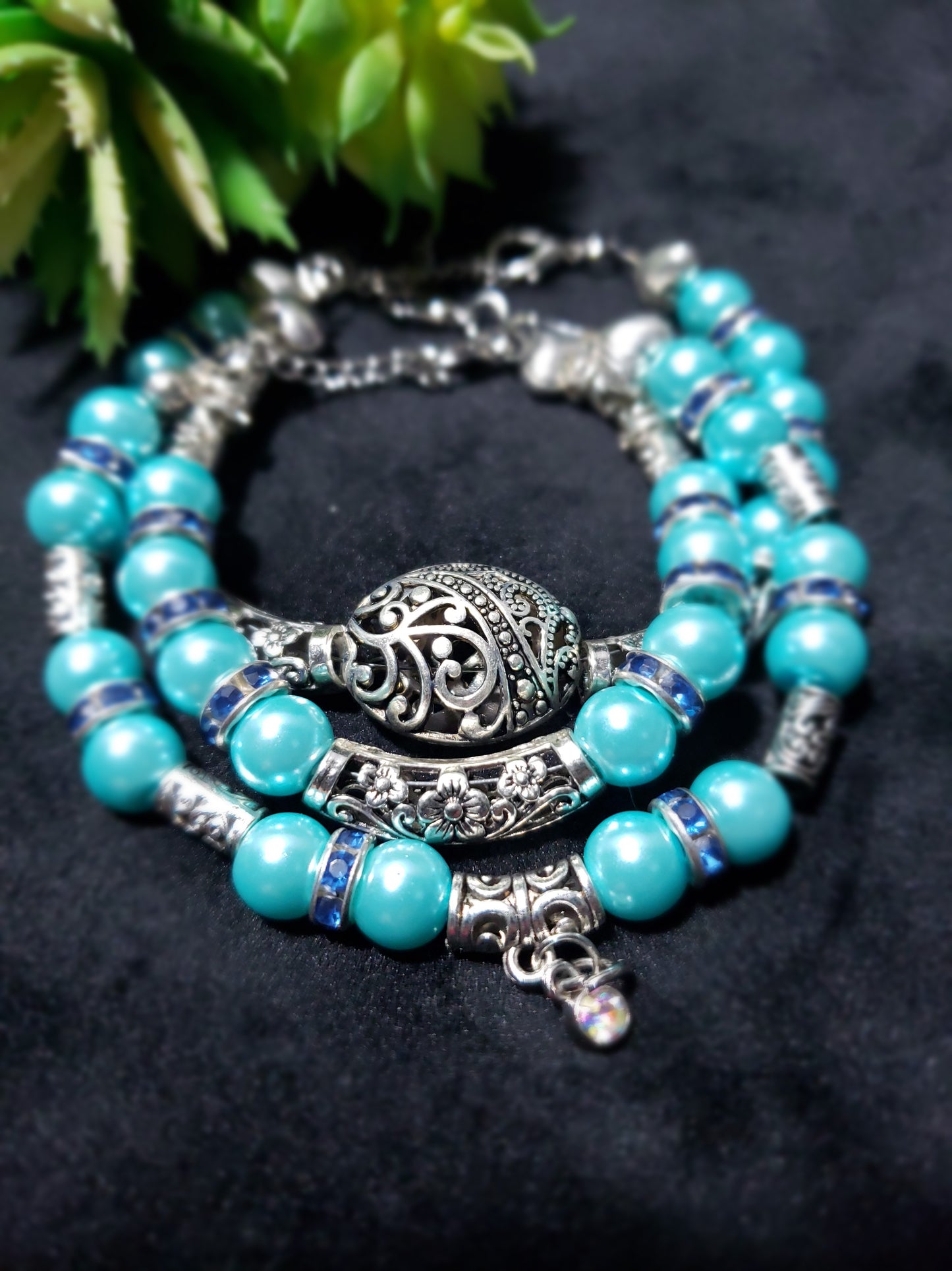 Blue beaded bracelet with silver charm on a dark background