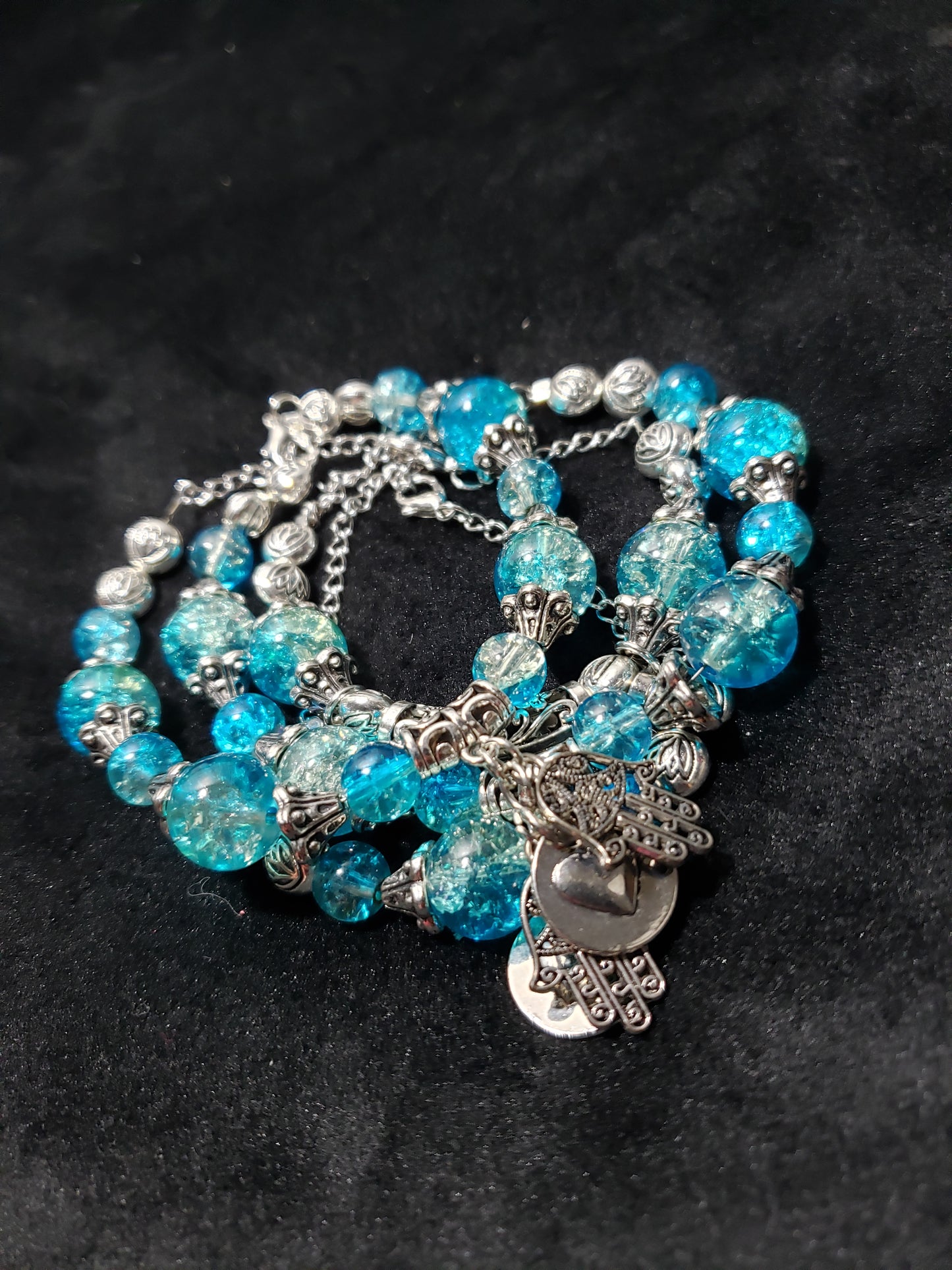 Blue beaded bracelet with silver charms on a black background