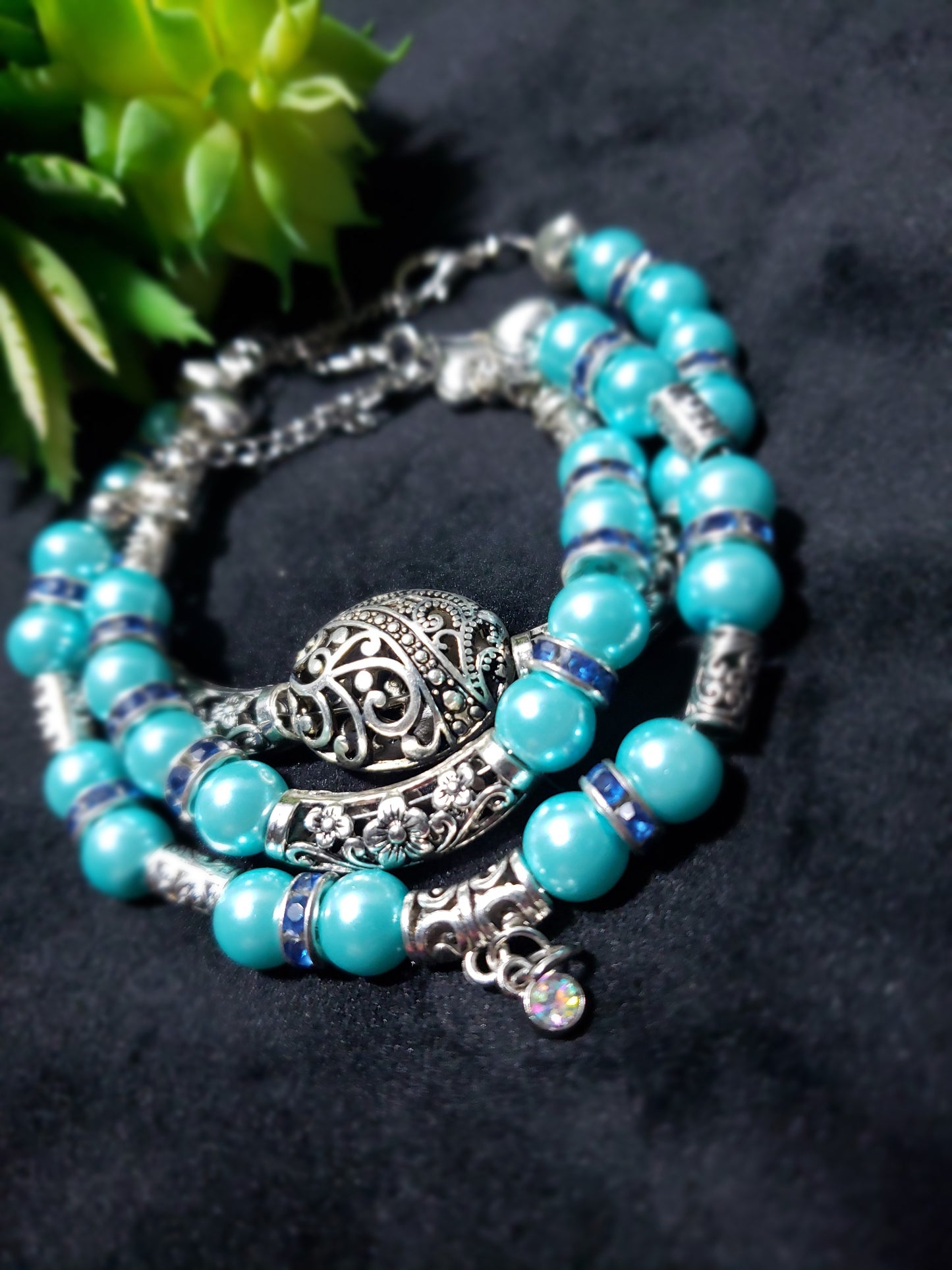 Blue beaded pearl bracelets with silver charm on a dark background