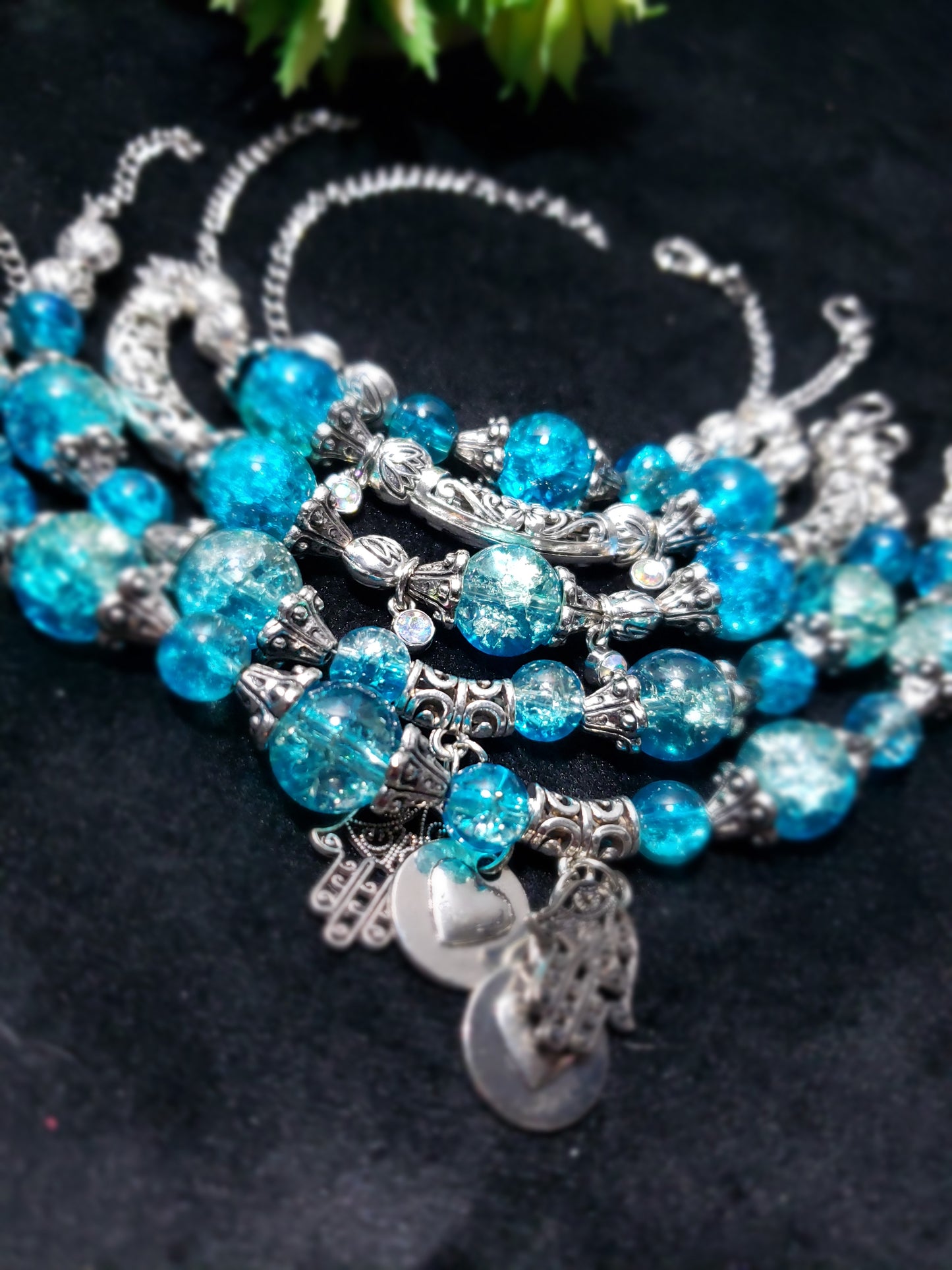 Blue crackle beaded bracelet with silver charms on a dark background