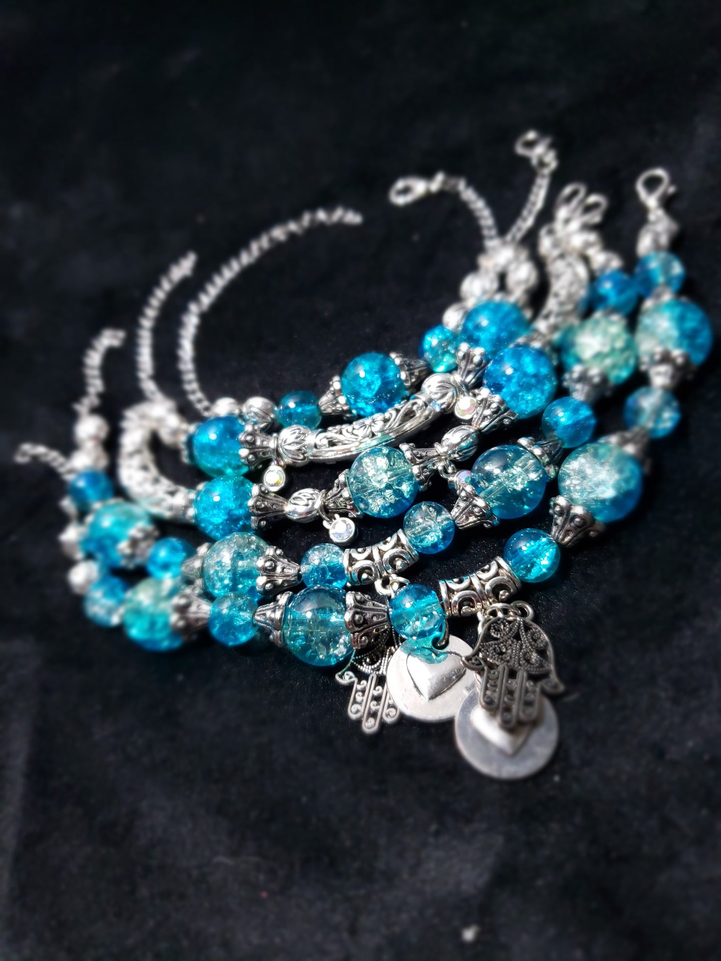 Blue crackle beaded bracelet with silver charms on a black background