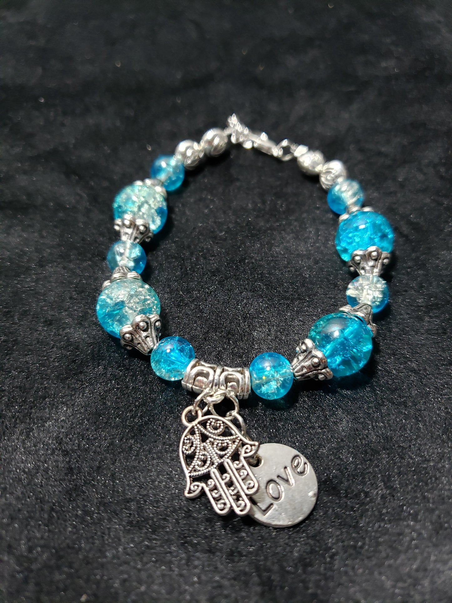 Bracelet with blue beads and silver charm on a black background