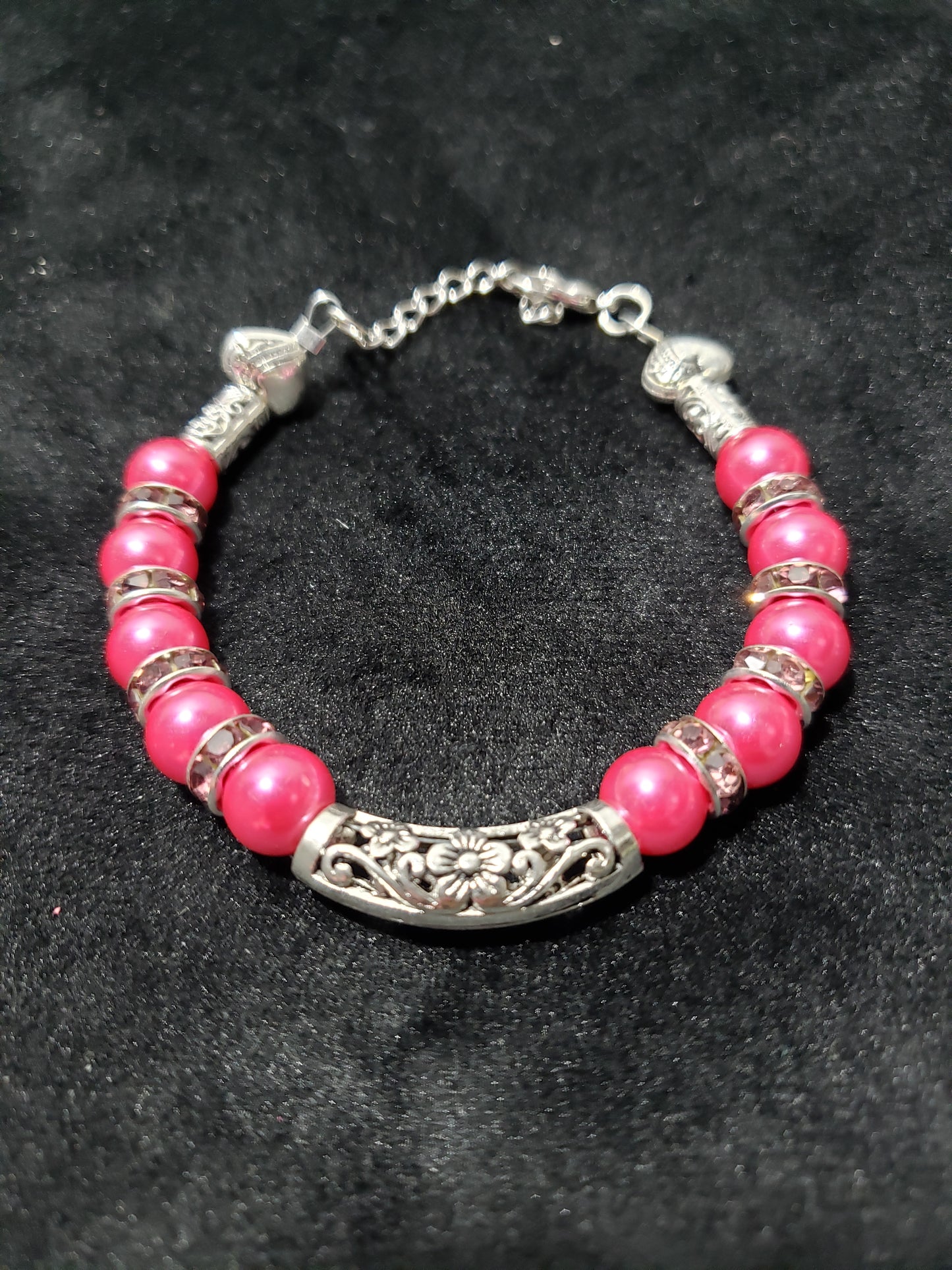 Bracelet with fuchsia beads and silver accents on a dark background