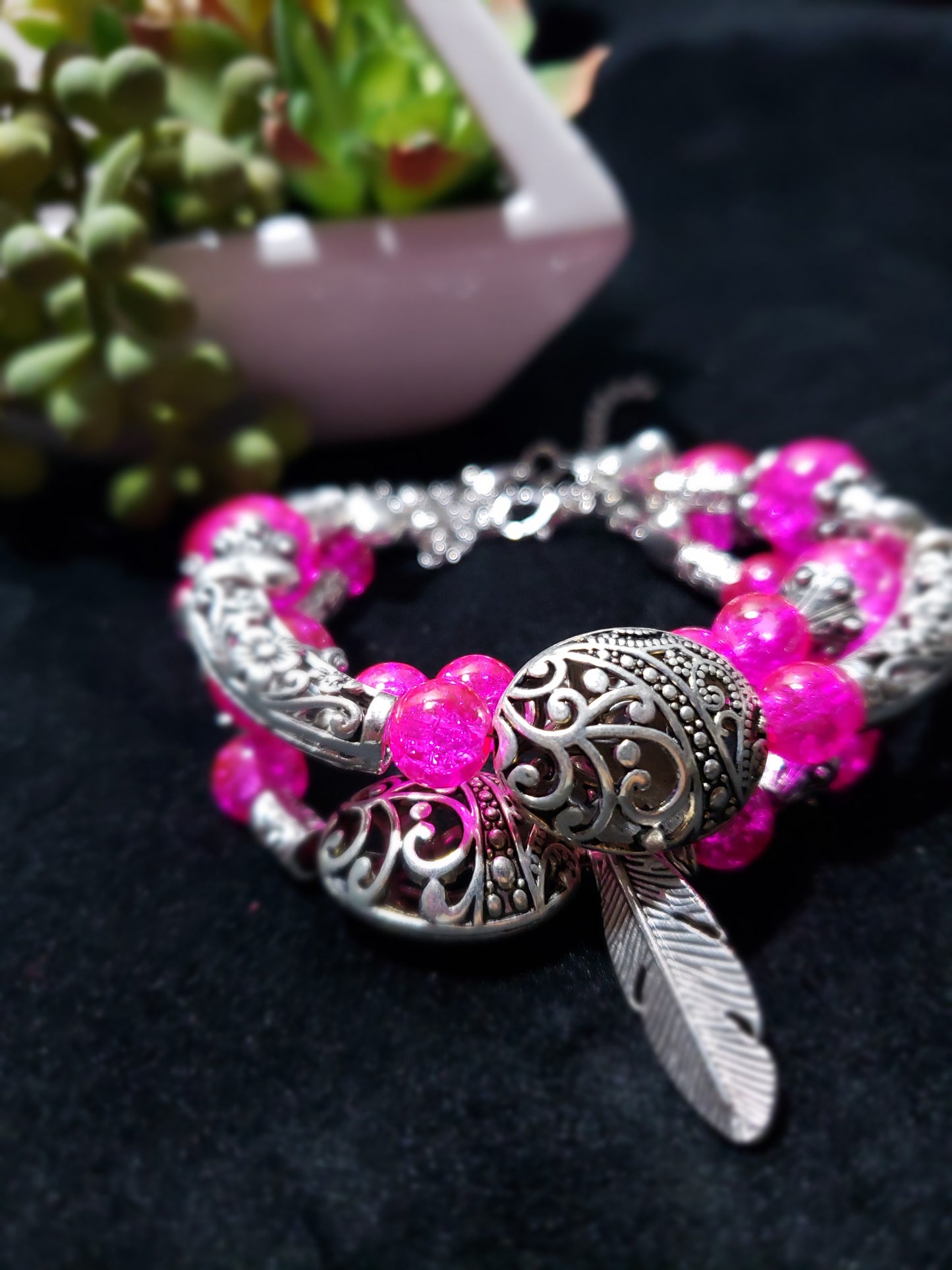 Bracelet with pink beads and silver bee design on a dark background