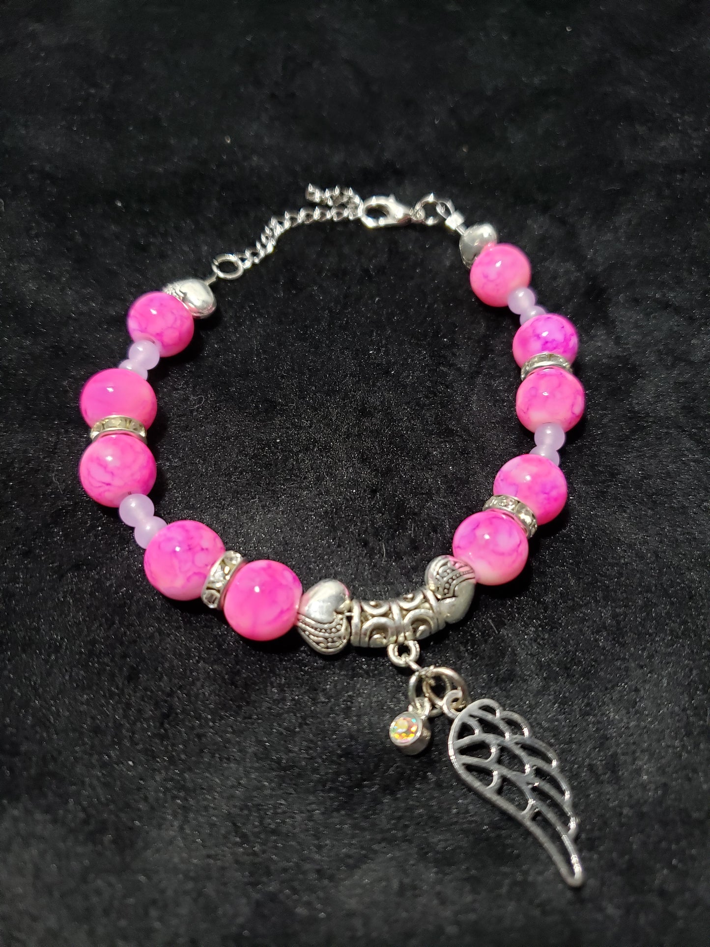 Bracelet with pink marble beads and angel wing charm on a dark background