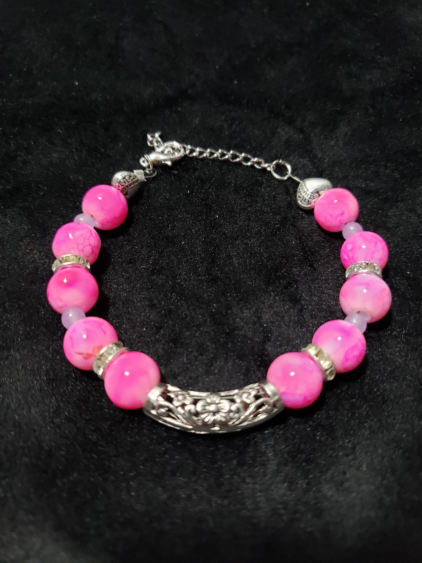 Bracelet with pink marble beads and silver accents on a black background