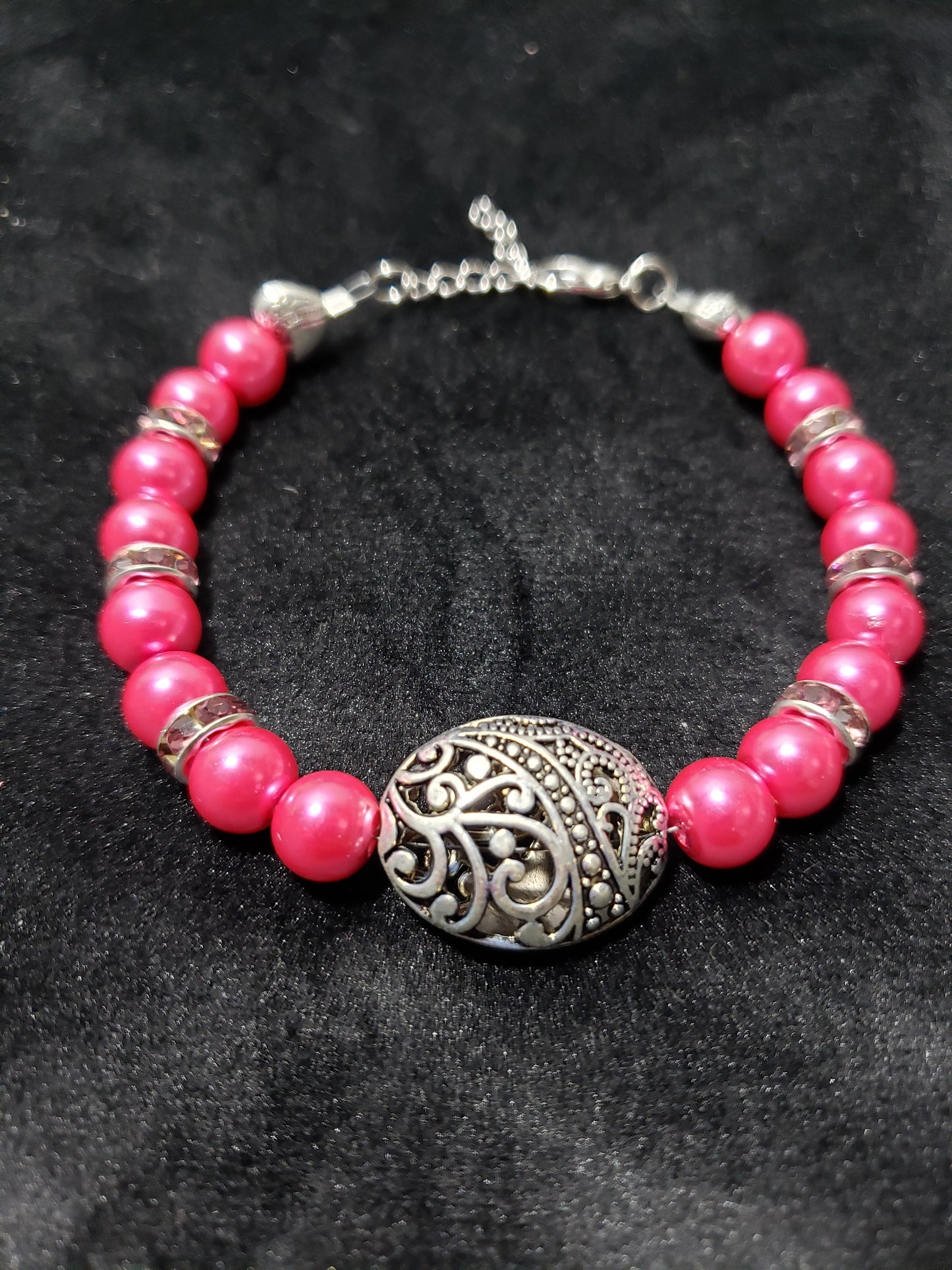 Fuchsia beaded bracelet with a silver clasp on a dark background
