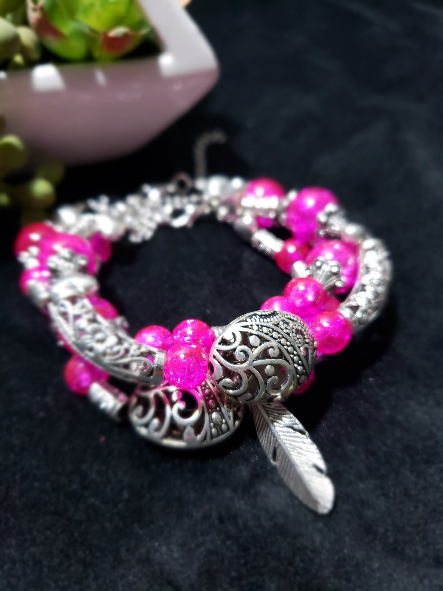Pink crackle beaded bracelet with silver clasp on a dark background
