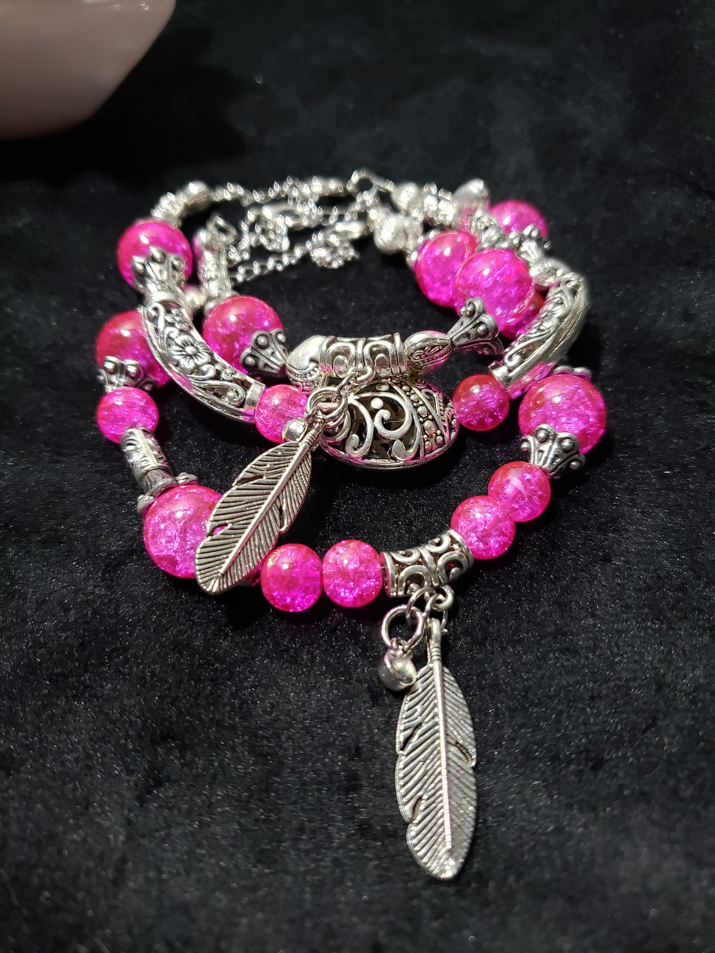Bracelet with pink beads and silver feathers on a black background