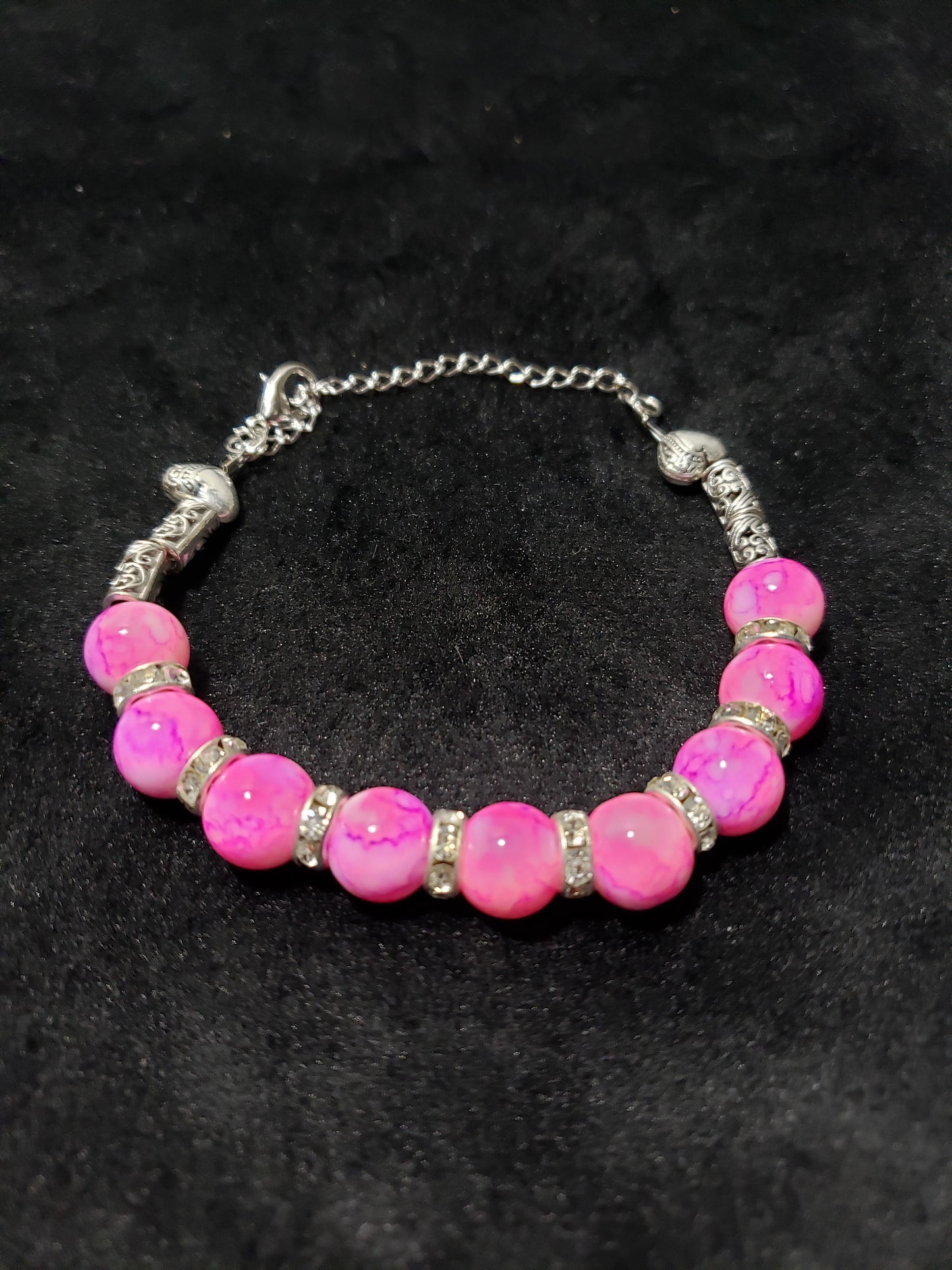 Pink marble beaded bracelet with silver accents on a black background