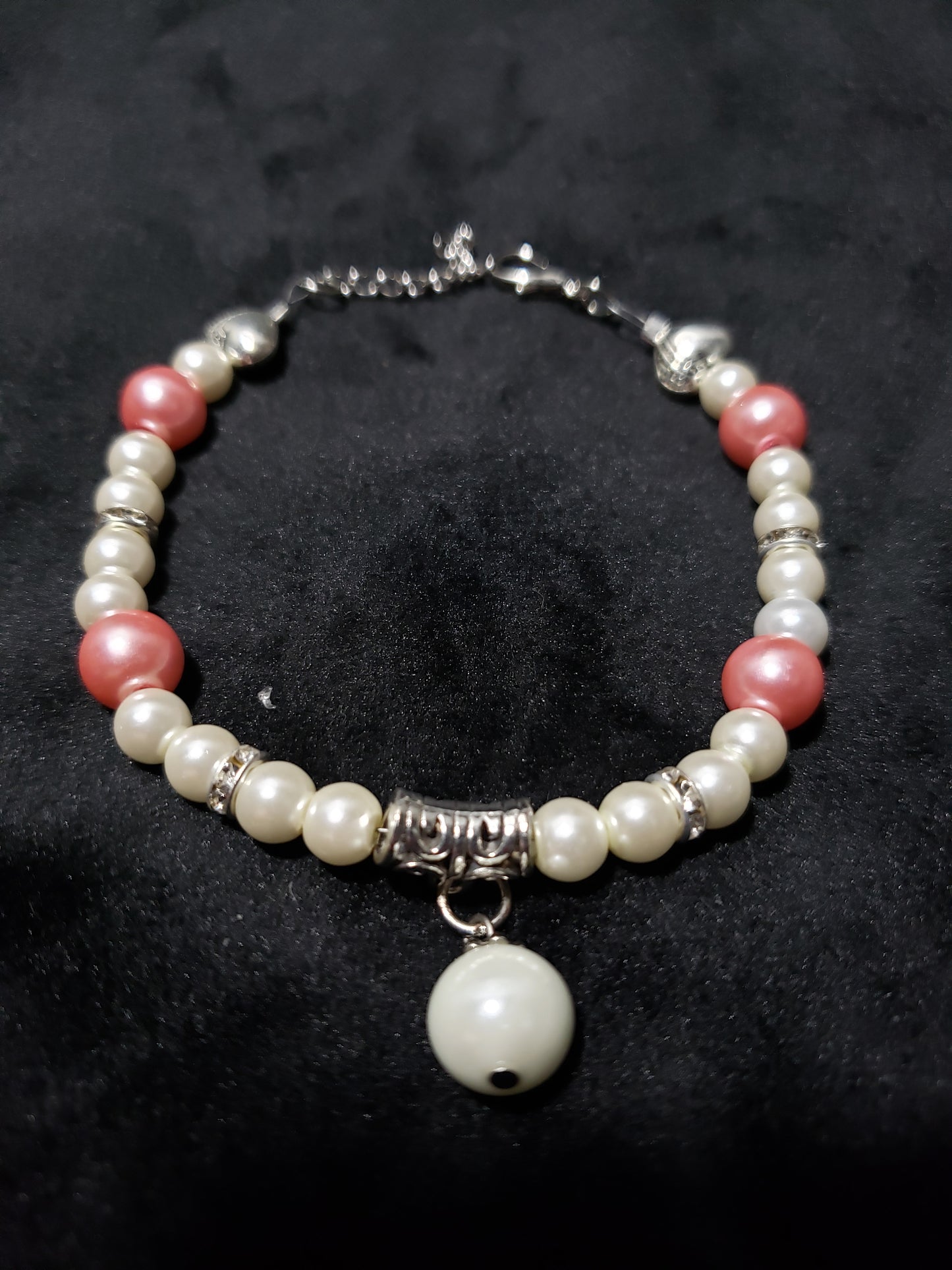 Beaded bracelet with white and pink beads on a dark background
