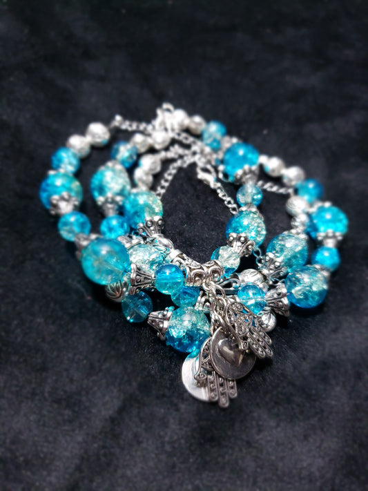 Blue Crackle beaded bracelet with silver charms on a dark background