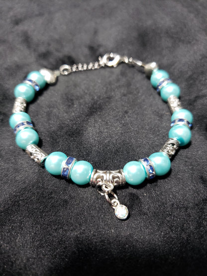 Blue beaded bracelet with silver accents on a black background