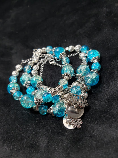 Blue beaded bracelet with silver charms on a black background