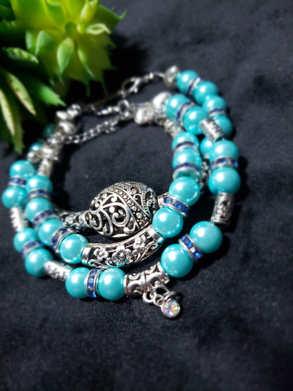 Blue beaded pearl bracelets with silver charm on a dark background