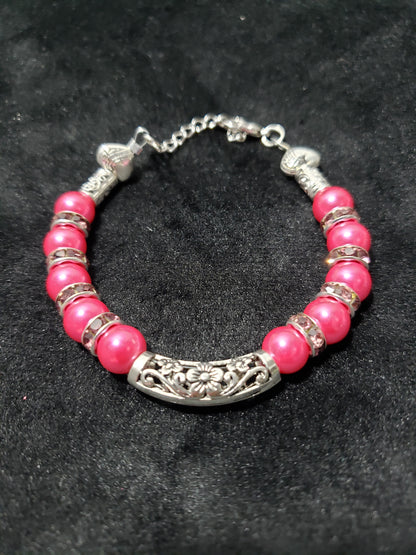 Bracelet with fuchsia beads and silver accents on a dark background