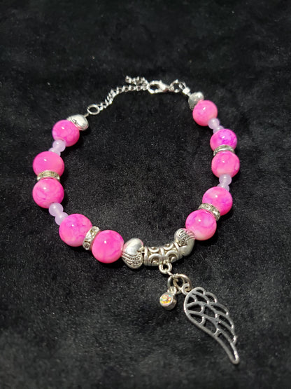 Bracelet with pink marble beads and angel wing charm on a dark background