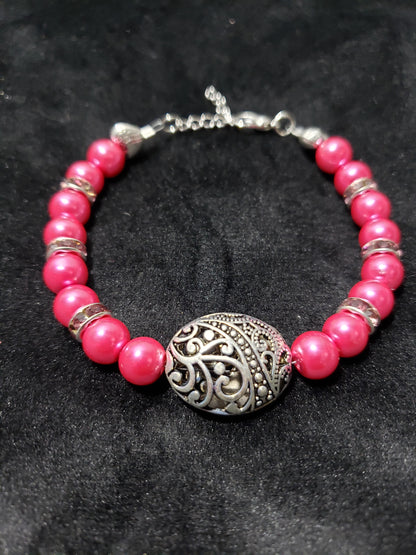 Fuchsia beaded bracelet with a silver clasp on a dark background