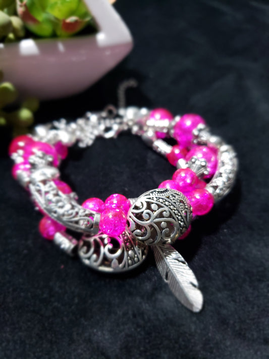 Pink crackle beaded bracelet with silver clasp on a dark background