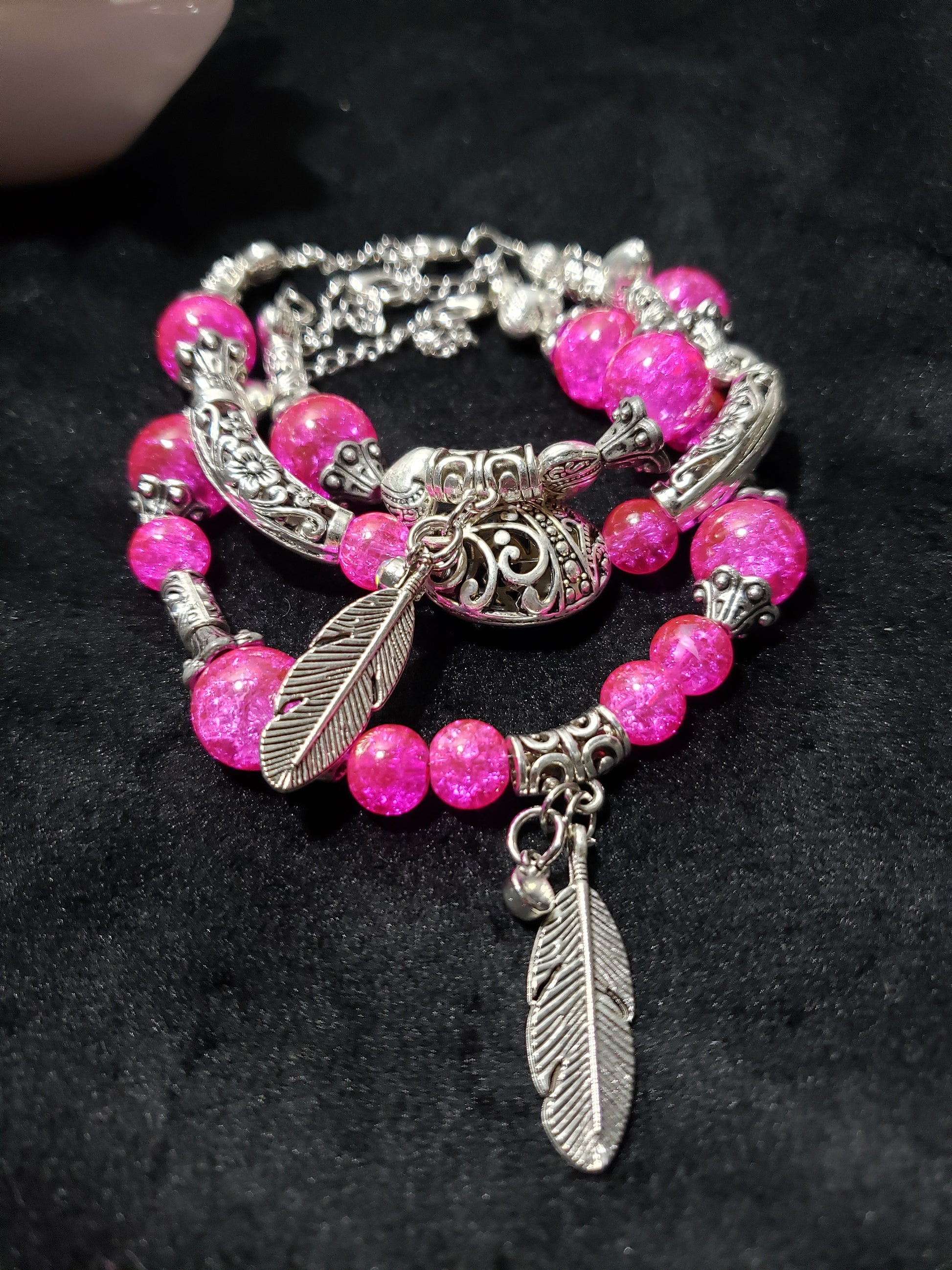 Bracelet with pink beads and silver feathers on a black background
