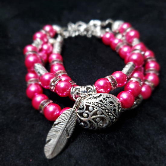 Fuchsia beaded bracelet with a silver feather charm 